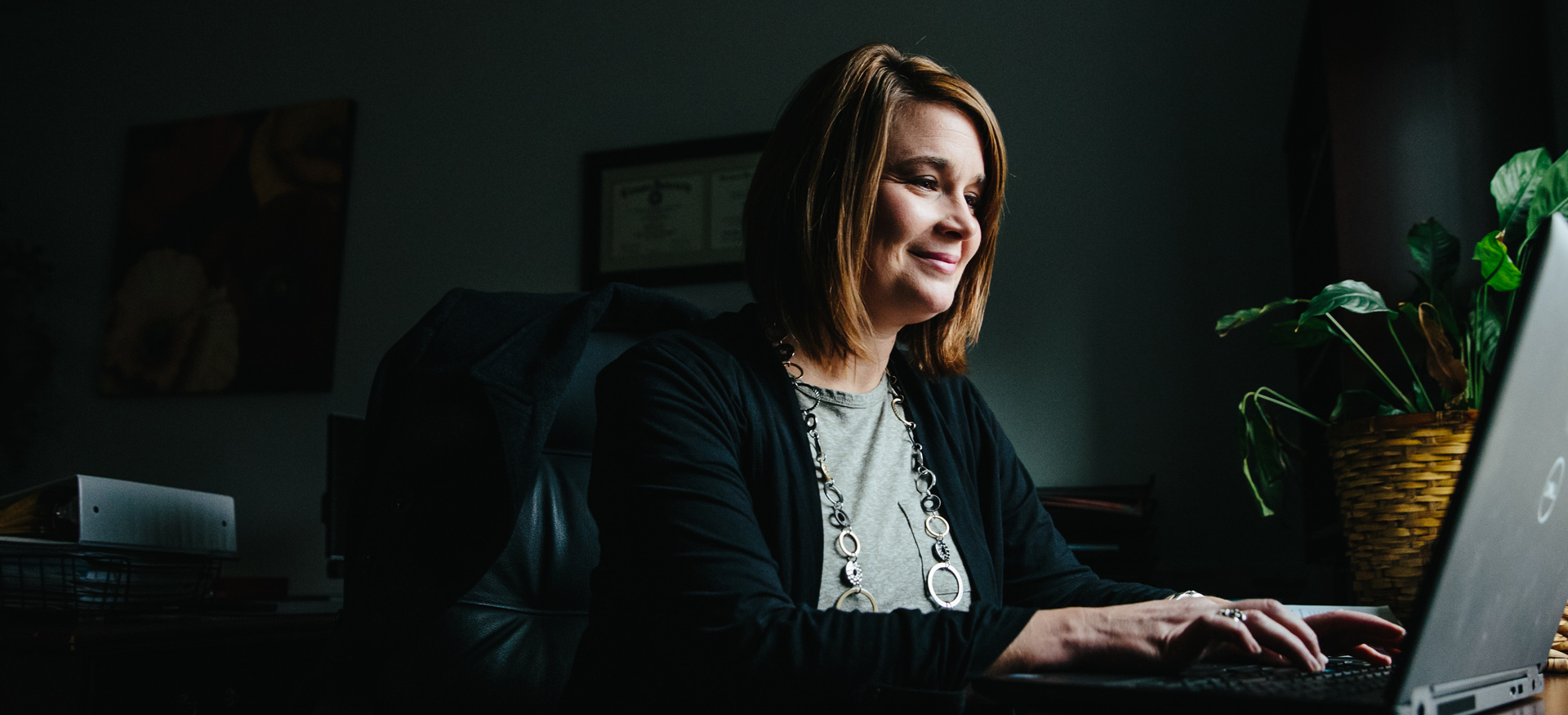 Educator working at a laptop and smiling.